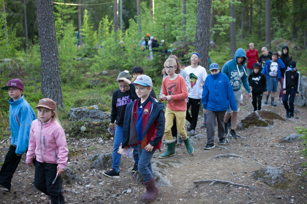 Lapsijoukko kulkee luontopolkua pitkin metsässä.